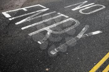 No Entry, white text road marking over dark urban asphalt pavement, background photo