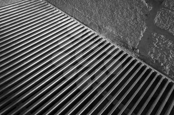 Steel grating of urban drainage system near concrete wall, abstract background photo
