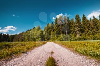 Rural road perspective under blue sky in summer day. Empty landscape background of Finland, toned photo