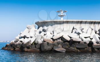 White beacon mounted on the end of concrete breakwater, structure for inner port protection