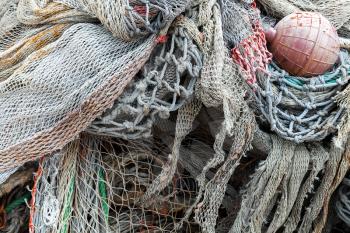 Old fishing nets with red float lay in port. Close-up background photo with selective focus