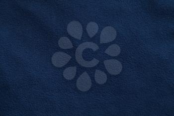 Texture of dark blue fleece, soft napped insulating fabric made from polyester