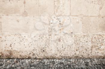 Rough stone wall with cobblestone ground, empty urban square interior, background photo texture