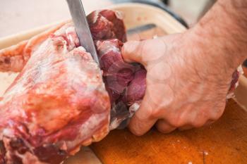 Lamb cutting, cook hands with knife, close-up photo, selective focus