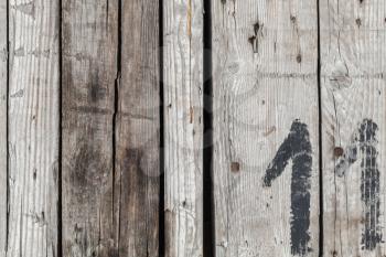 Rough wooden wall with black painted number 11, flat frontal background photo texture