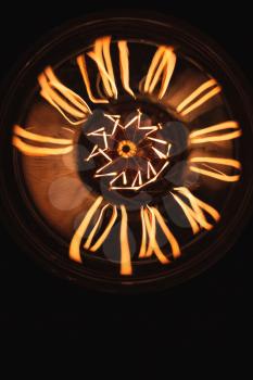 Retro stylized large tungsten lamp glowing over dark background, top view, close-up vertical photo with selective focus and shallow DOF