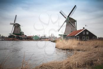 Old Windmills on coast of Zaan river, Zaanse Schans historic town, popular tourist attraction of Netherlands
