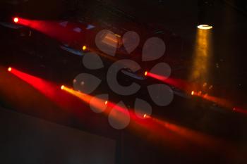 Red scenic spot lights with strong beams in smoke over dark background, modern stage illumination equipment