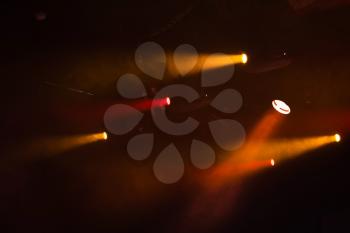 Red and orange spot lights with strong beams in smoke over dark background, modern stage illumination equipment
