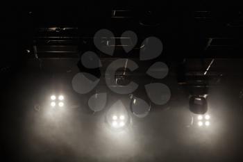 Scenic strobe lights in smoke over dark background, stage illumination equipment