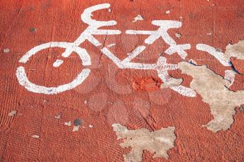 Bicycle lane. Grungy white road marking over red painted concrete road