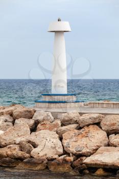 White lighthouse tower standing on a breakwater at the entrance to Ayia Napa port, Cyprus island, Mediterranean Sea