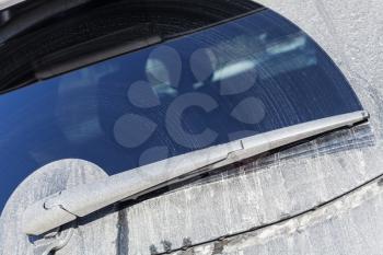Close-up photo of car wiper on dirty rear window of modern SUV car