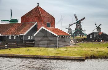 Wooden barns and windmills on Zaan river coast, Zaanse Schans town, popular tourist attractions of the Netherlands. Suburb of Amsterdam