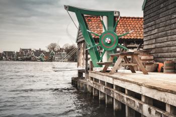 Vintage wooden crane mounted near windmill. Zaanse Schans town, popular tourist attractions of the Netherlands. Suburb of Amsterdam