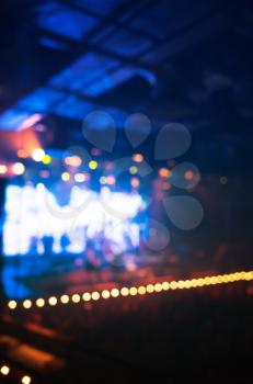Blurred vertical photo background, life music concert stage with colorful illumination and crowd of people