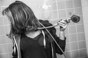 Sad European teenage girl in shower bath. Depression mood concept, black and white photo