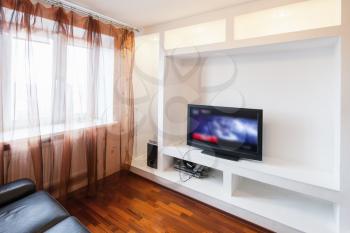 Empty room interior with black sofa and tv in white wall installation