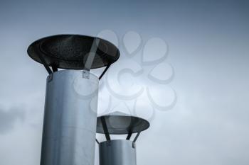 Two round steel chimneys over blue sky background