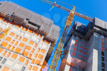 Construction crane and concrete living house under construction. Block of flats development