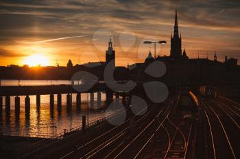 Cityscape with subway train crossing the bridge of Gamla Stan at sunset, Stockholm, Sweden