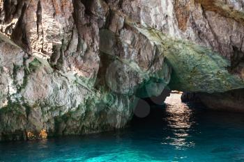 Coastal rocks of Capri island, small grotto with shining sea water inside