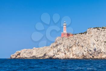 Punta Carena. Red lighthouse tower stands on rocky coast of Capri island, Italy
