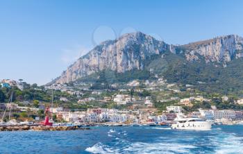 Port of Capri, Italy. Pleasure boats go near breakwater with red lighthouse