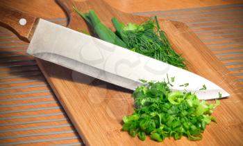 Sliced greens with knife on wooden cutting board