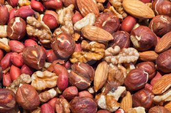 Background texture of roasted mixed nuts. Peanut, hazelnut, almond and walnut