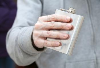 Closed steel small flask in man's hand