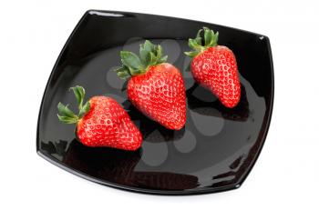 Three fresh strawberries on black saucer isolated on white