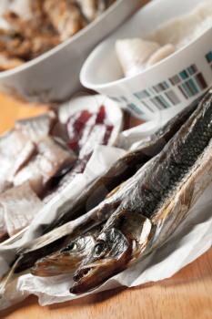 Assorted fish on wooden table. Salted smelt fish and herring fillet