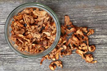 Dried Chanterelle mushrooms in glass jar on wooden table. Top view