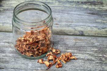 Dried Chanterelle mushrooms in glass jar on wooden surface