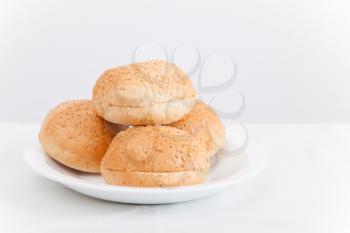 Small buns for hamburgers lay on white plate