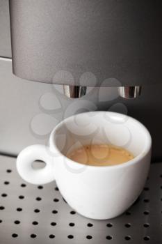 Small cup of espresso stands in modern automatic coffee machine