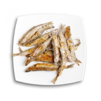 Pile of fried smelts fish lays on a white plate, top view isolated on white background with soft shadow