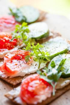 Healthy food. Sandwiches made of Finnish rye crisp bread, soft cheese, cucumber, tomato, parsley and black pepper