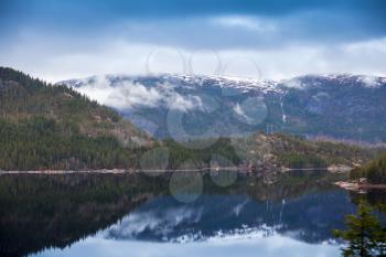 Rural Norwegian landscape with still lake water and mountains in spring