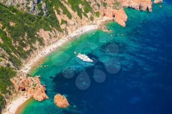 Corsica, French island in Mediterranean Sea. Coastal landscape with rocks and pleasure motor yacht, bird eye view