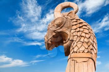 Carved wooden dragon on forepart of the ancient Viking ship above dramatic blue sky