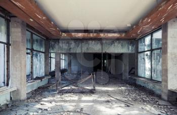 Abandoned building interior. Corridor perspective with dirt on the floor and broken windows. Vintage tonal photo filter effect, old style