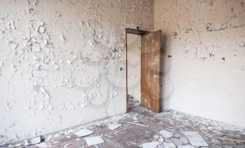 Abandoned industrial building interior. Cracked paint on walls and open wooden door