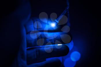 Blue LED (light emitting diodes) lights and male hand on black background