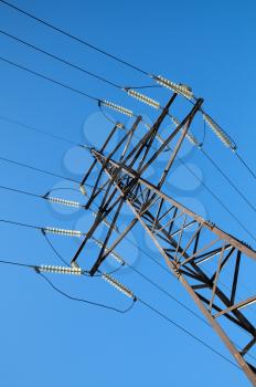 High voltage power lines and steel pylon in front of clear blue sky