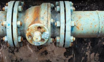 Old rusted valve on blue industrial pipeline