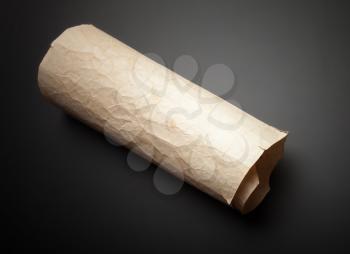 Old yellow crumpled paper roll on black table