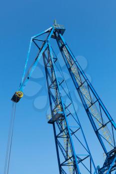 Upper part of big industrial port crane above blue sky