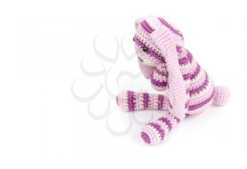 Knitted rabbit toy sitting isolated on white background with soft shadow